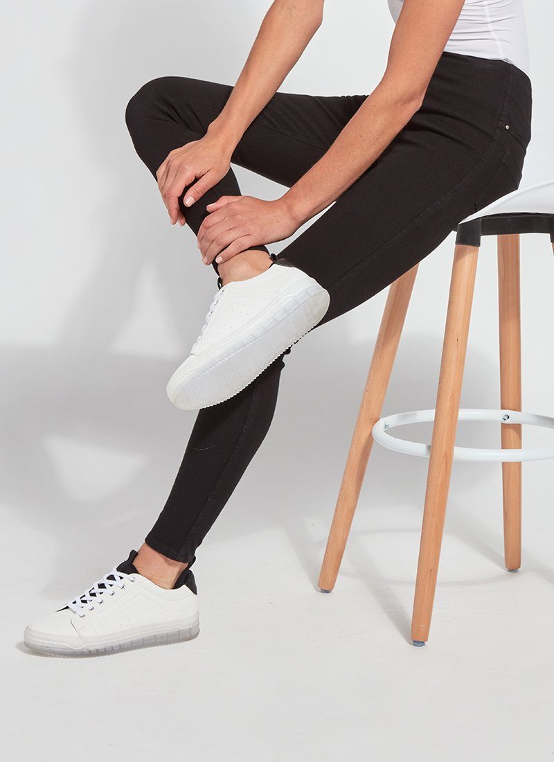 color=Black, Seated side view of black, toothpick denim jean leggings with patented concealed waistband, seen from waist down