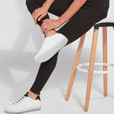 color=Black, Seated side view of black, toothpick denim jean leggings with patented concealed waistband, seen from waist down