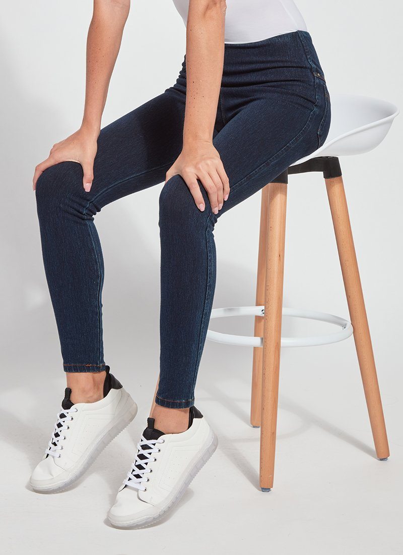 color=Indigo, Front angle, seated view of indigo toothpick denim jean leggings with patented concealed waistband