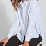 color=White, seated side view, slim fit women’s button up shirt with curved hem, made with wrinkle resistant microfiber